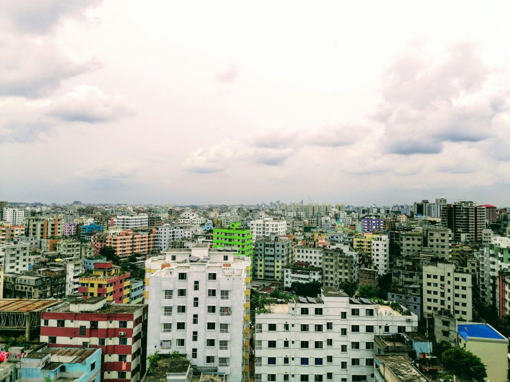 Aerial view of Dhaka's urban landscape under a cloud-filled sky, showcasing vibrant architecture.