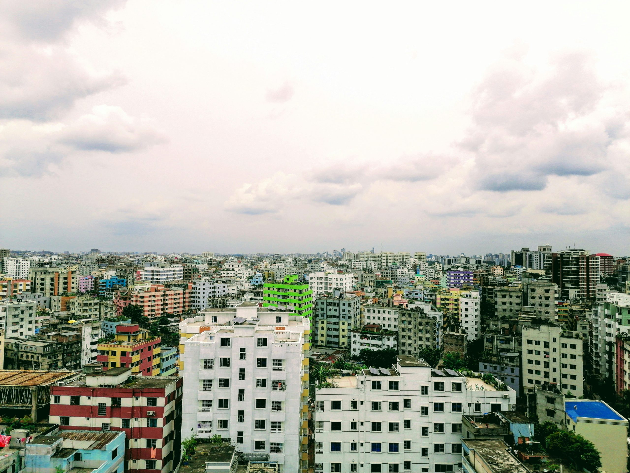 Aerial view of Dhaka's urban landscape under a cloud-filled sky, showcasing vibrant architecture.